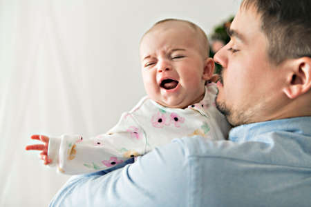 Gentle father comforting crying baby at home