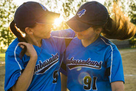 A mother and daughter baseball players together on the playgroundの写真素材