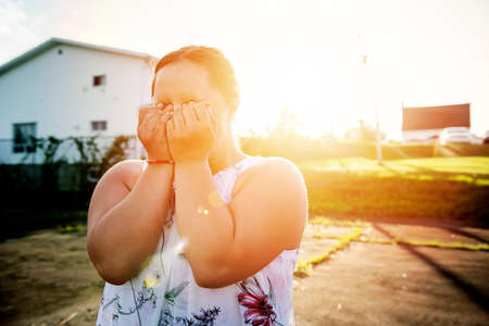 A Portrait of trisomie 21 adult girl outside at sunset having problemの写真素材