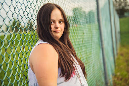 A Portrait of trisomie 21 adult girl outside at sunset