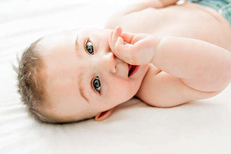 cute baby boy lying on a white bed