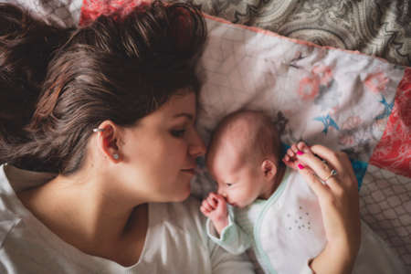 A Portrait of a beautiful mother with her newborn baby in the bedroomの写真素材