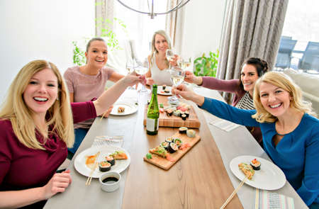 Group of attractive mature people eating sushi at homeの写真素材