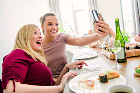 Two funny mature people eating sushi at home taking photoの写真素材