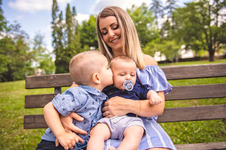 Happy mother having fun with his two son baby on the park