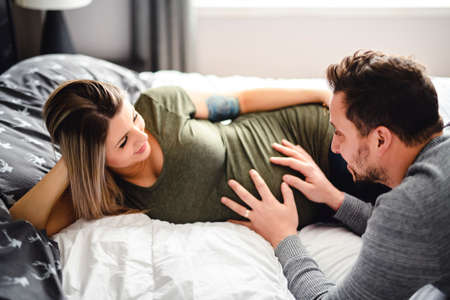 The parents in bed expecting a little baby, Romantic moments for pregnant couple