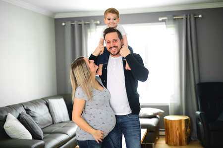 A Beautiful pregnant mother and father with her children at the living room