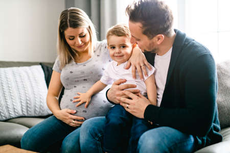 A Beautiful pregnant mother and father with her children at the living roomの写真素材
