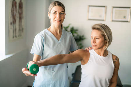 A Modern rehabilitation physiotherapy worker with woman clientの写真素材