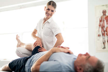 A Modern rehabilitation physiotherapy worker with senior clientの写真素材