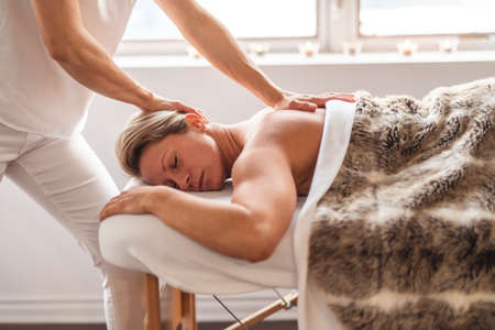 A Woman enjoying spa treatment at salon with masseur worker