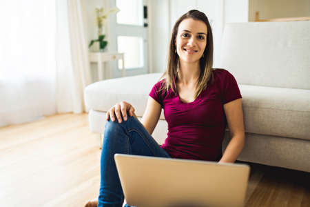 Brunette having good time on the living room with laptopの写真素材