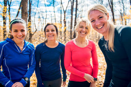 woman group out running together in an autumn park they run a race or train in a healthy outdoors lifestyle conceptの写真素材
