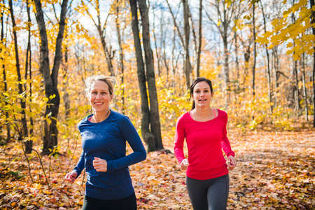 Two running woman jogging in autumn natureの写真素材