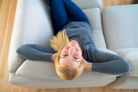 Relaxed woman enjoying rest on comfortable sofa, calm attractive girl relaxing on couchの写真素材