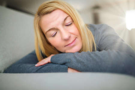 Relaxed and tired woman enjoying rest on comfortable sofa, calm attractive girl relaxing on couch
