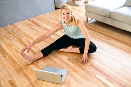 Portrait of fit woman training in her living room with laptop