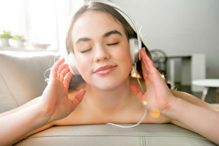teenage girl at home with headphones, listening music.の写真素材