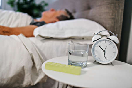 Unhealthy mature woman lying in bed, taking medicine from cold or insomnia