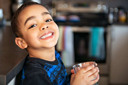 Cute African American boy drinking milk at home