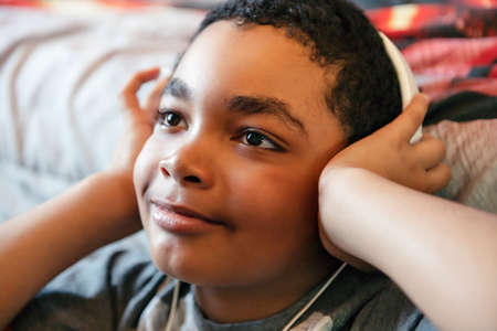 A Portrait of a sweet young boy listening to music on headphones