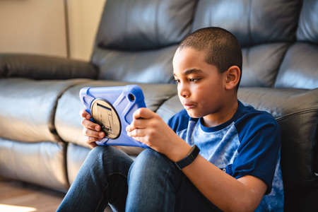 A black boy with tablet in the living room at home