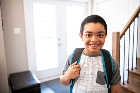 A child boy coming home passing through the door after schoolの写真素材