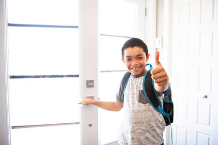 A child boy coming home passing through the door after schoolの写真素材