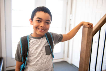 A child boy coming home passing through the door after school