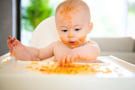 A Little baby eating her dinner and making a messの写真素材