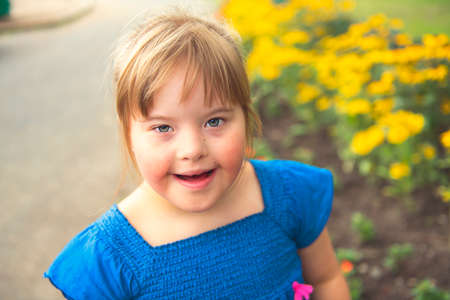 A portrait of trisomie 21 child girl outside having fun on a park
