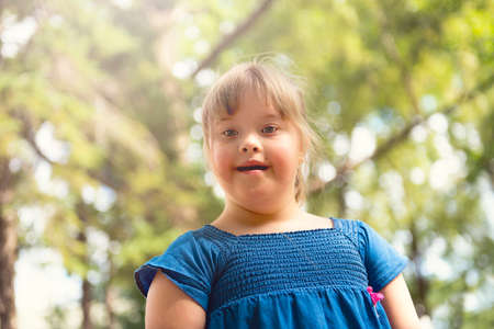 A portrait of trisomie 21 child girl outside having fun on a park