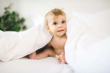 Cute happy baby boy in diaper on bed