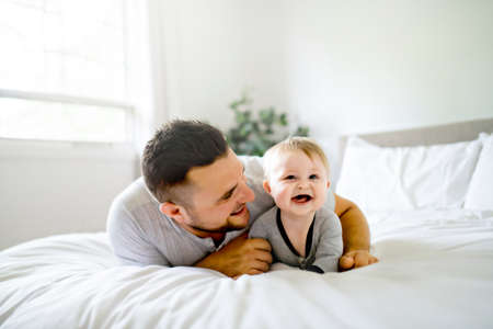 A Father with cute baby son on bed at home