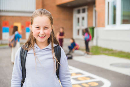 A student school girl on the playground on the first day of class