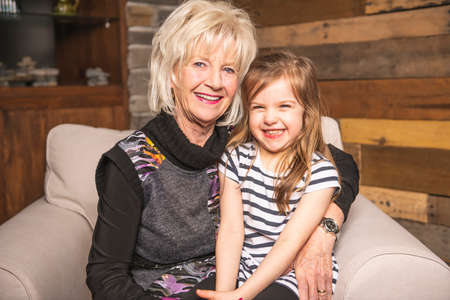 Portrait of grandmother with their little child sitting on sofa at home