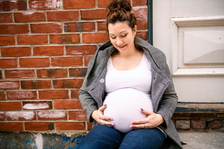 Pregnant girl outside on a city background