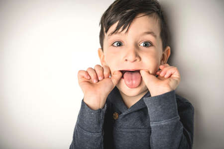 close portrait of a five years old boy over white doing grim
