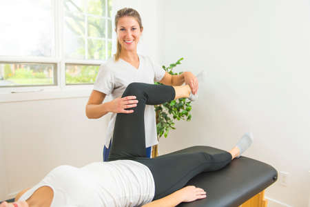 A Modern rehabilitation physiotherapist at work with client. Working on knee.の写真素材