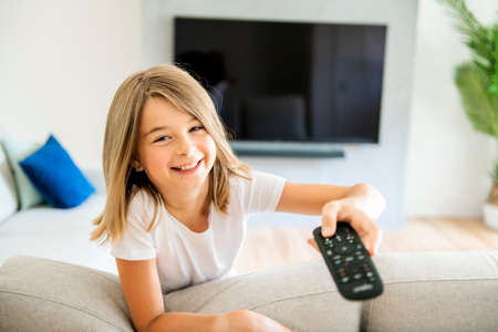 A girl holding remote control and watching TV show