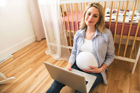 Attractive young pregnant woman with laptop