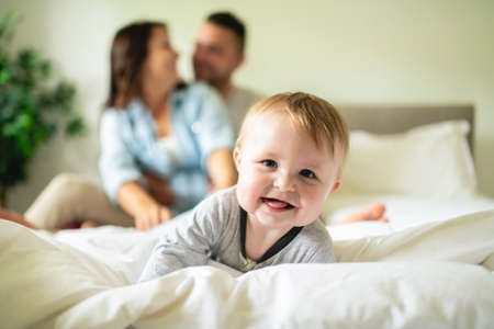 happy family mother, father and son at home in bed
