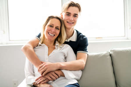 A people and family happy teen boy with mother on sofa at homeの写真素材