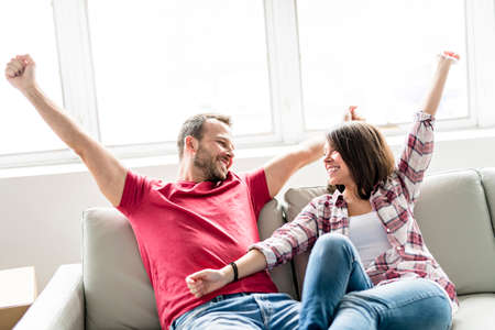 Couple sitting together on sofa at home happy to move from homeの写真素材