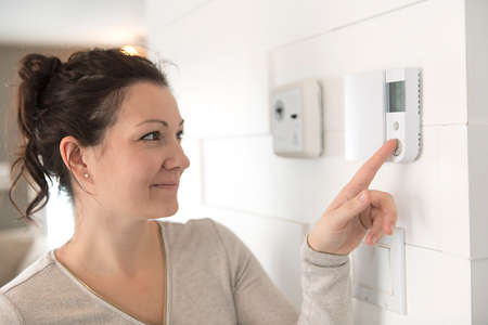A nice woman set the thermostat at house.