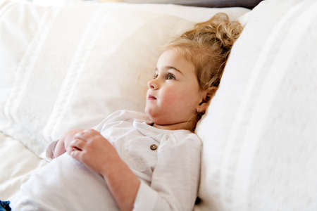 young daughter two years old relaxing in bed, positive feelingsの写真素材