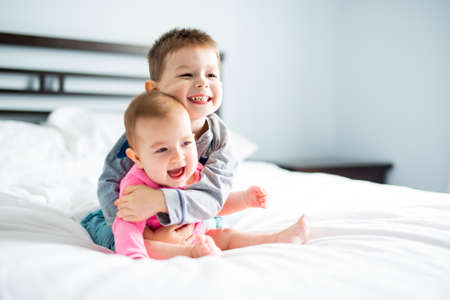 A baby and his brother on bed having funの写真素材