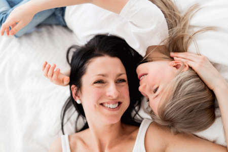 Mother and daughter enjoy in bed at home