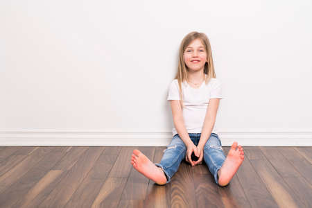 Happy small five years old girl with straight hair over white background at homeの写真素材