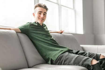Handsome confident young man relaxing at home on the sofa